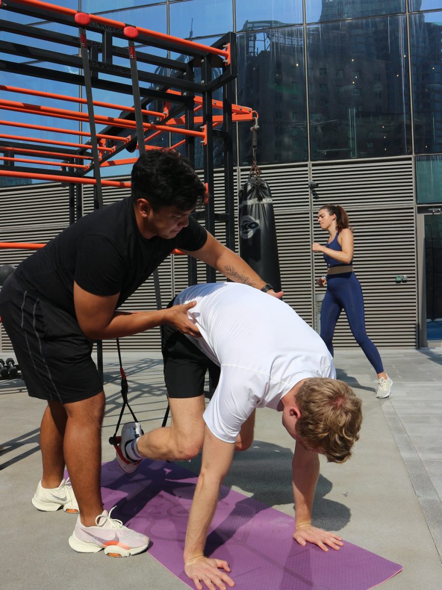 An ATHLI coach guiding a member through a stretch outdoors