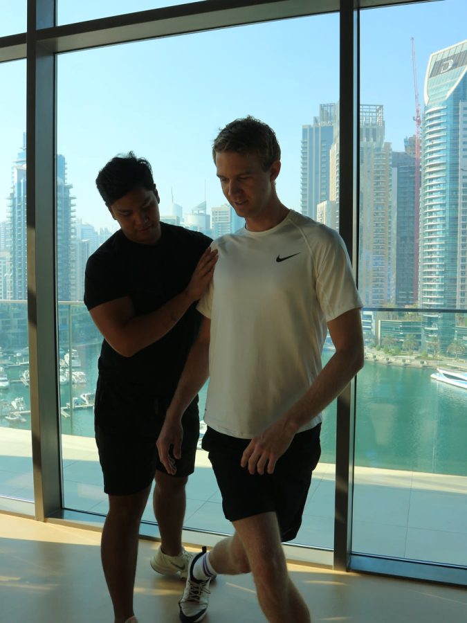 Two ATHLI members walking through a warm-up overlooking Dubai Marina