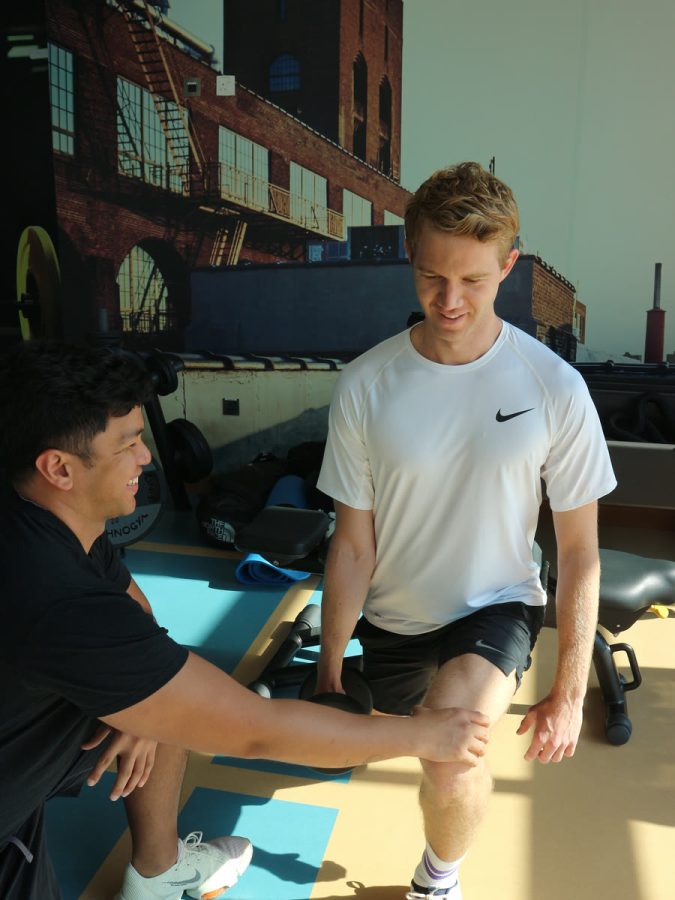 An ATHLI coach guiding a member through a mobility stretch