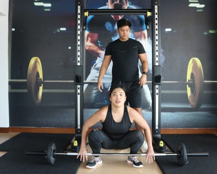 An ATHLI member taking on a squat challenge with her coach