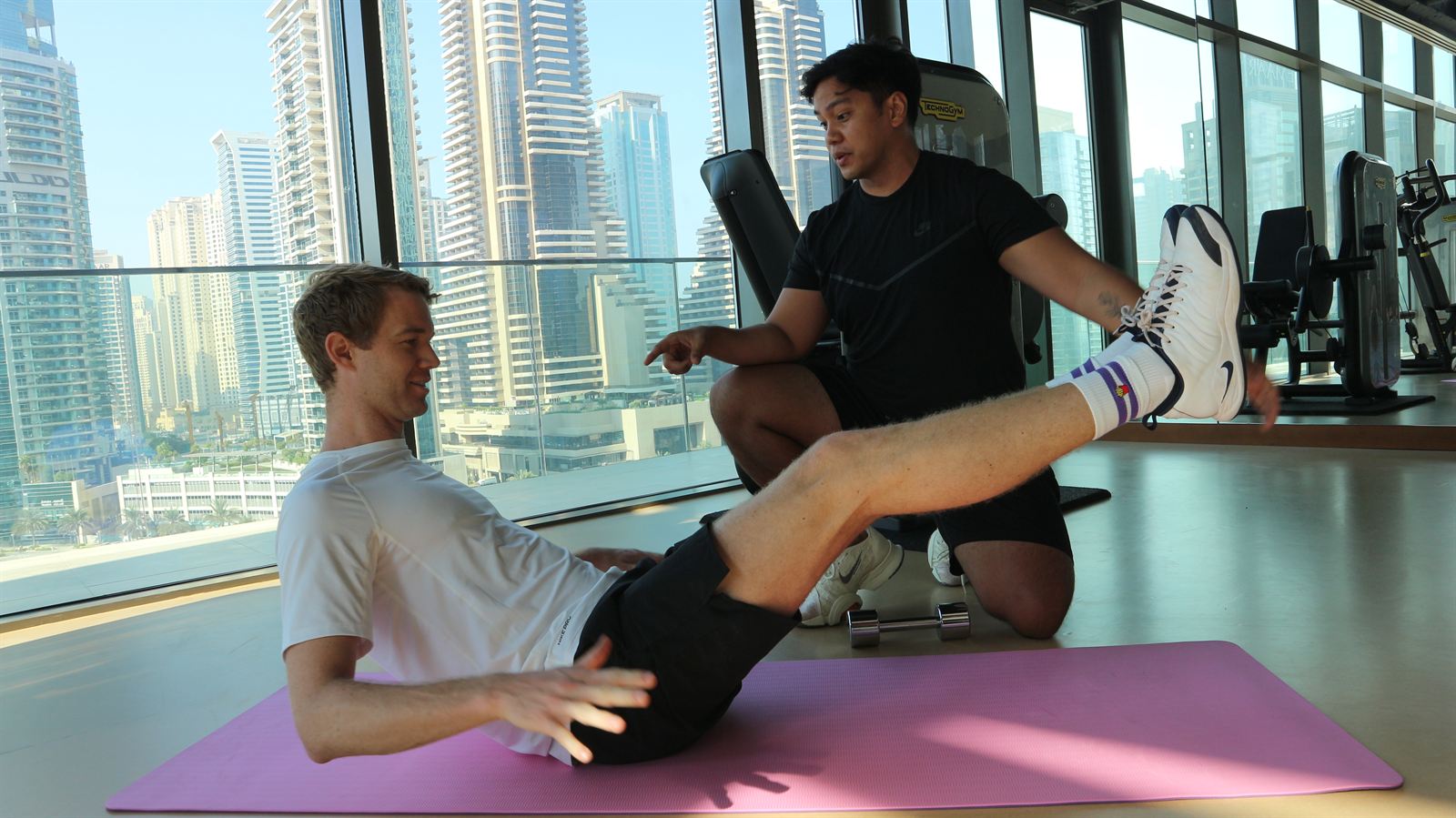 An ATHLI coach talking a member through a seated core hold