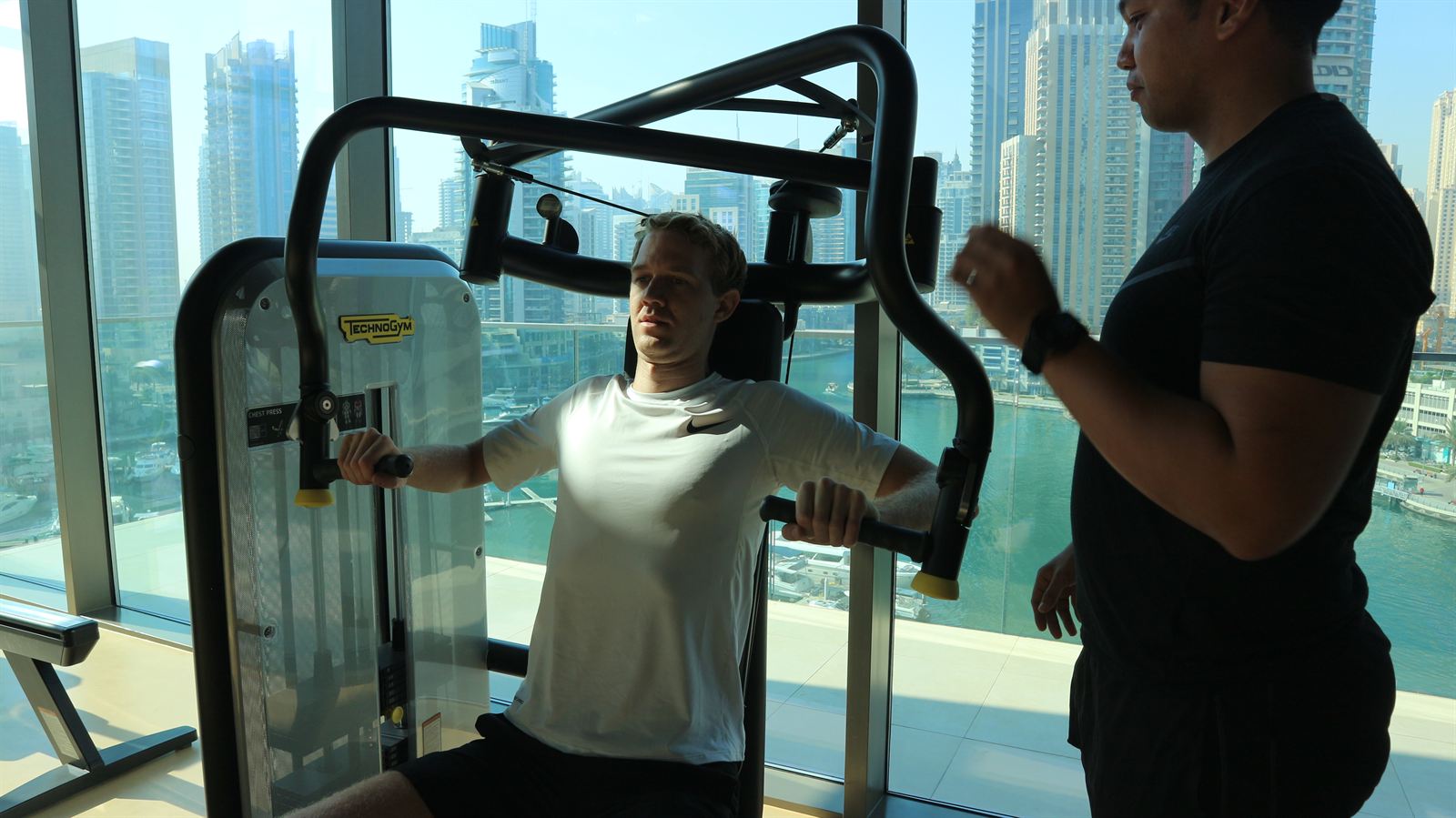 An ATHLI member working through a press machine with his coach beside him